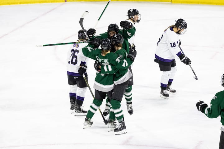 Boston players, wearing green home uniforms, celebrate the first goal in franchise history. 