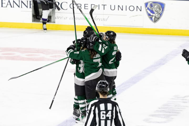 In their green home uniforms, teammates celebrate Megan Keller's goal with her.
