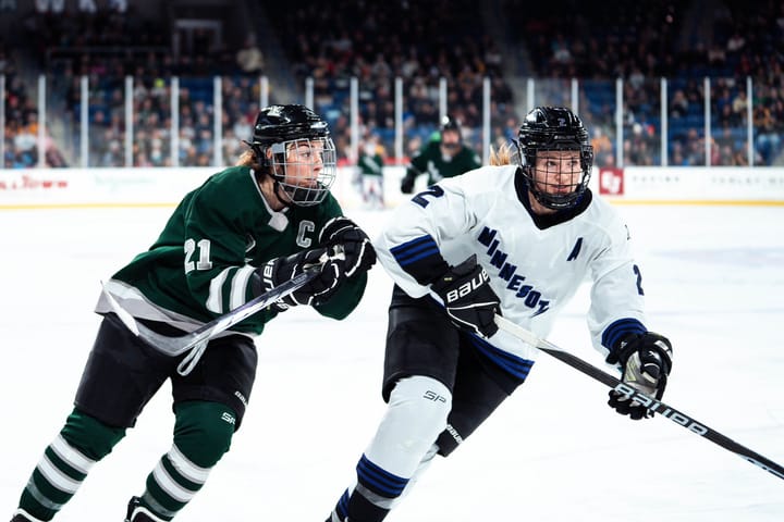 Hilary Knight and Lee Stecklein skate towards a loose puck.