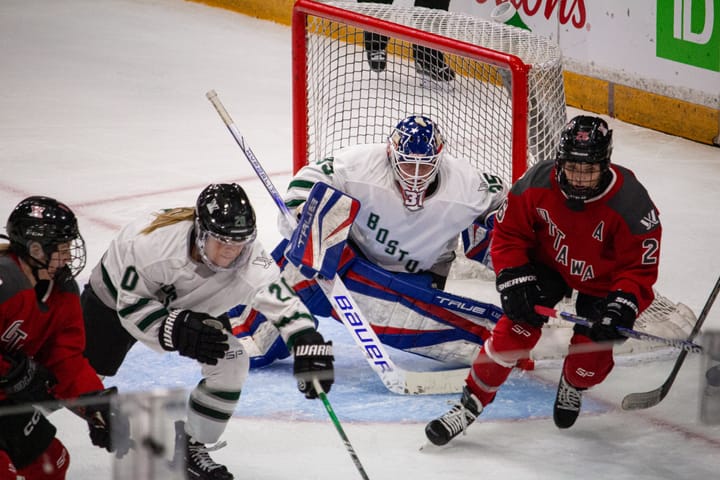 Emily Clark chases a puck in front of Aerin Frankel in the Boston net.