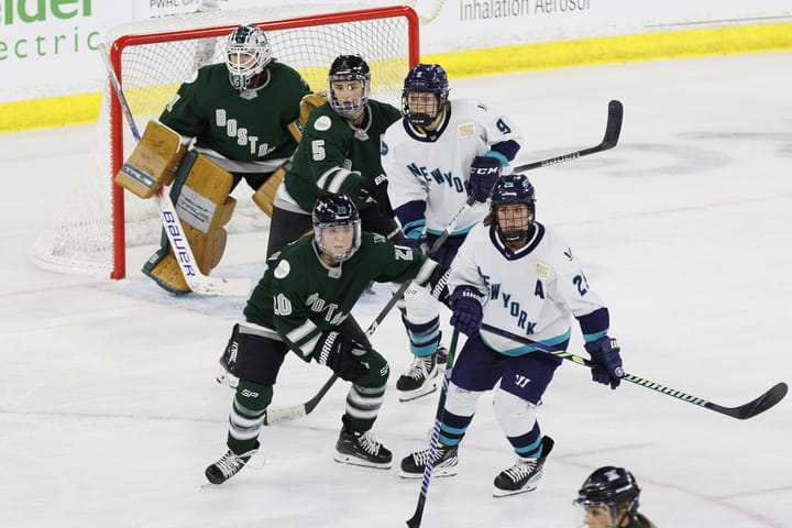 Boston and New York players battle in front of Aerin Frankel. Boston is in green and New York is in white. 