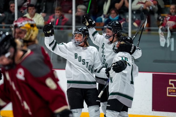Wearing their white away uniforms, Boston players celebrate Amanda Pelkey's overtime winner with her against Montréal.