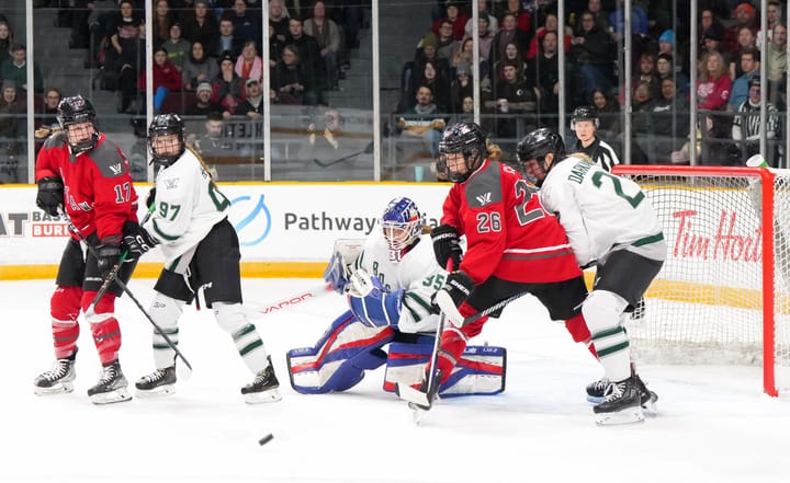 Boston players, wearing white, battle defensively with Ottawa, wearing red, in front of Aerin Frankel.