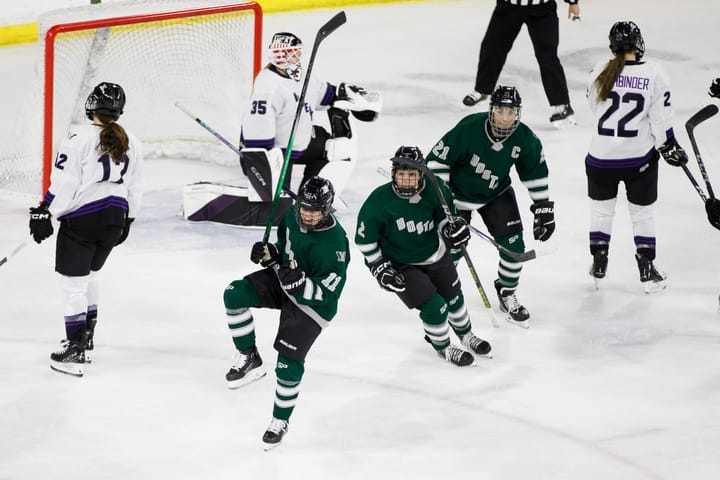 Alina Müller celebrates her goal against Minnesota with Emily Brown and Hilary Knight. All are wearing green home uniforms.
