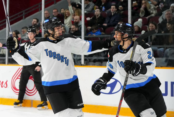 Nurse goals in for a hug with Spooner to celebrate a goal. Both are wearing their white away uniforms.