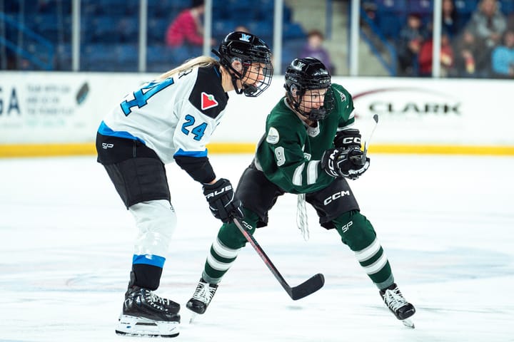 Sophie Shirley and Natalie Spooner prepare to make a play on the puck. Shirley is in green, while Spooner is in white.