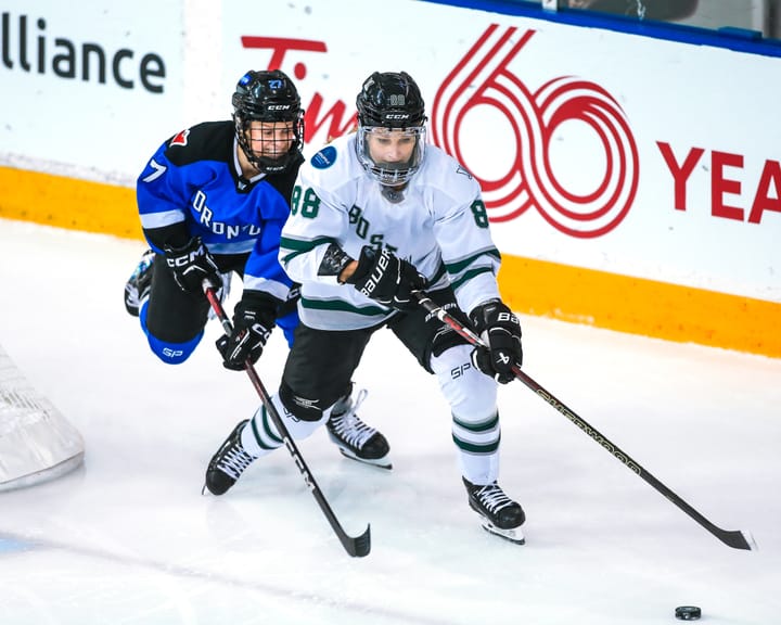 Tapani protects the puck from Maltais. Tapani is on the right (outside) wearing white, Maltais is in blue.