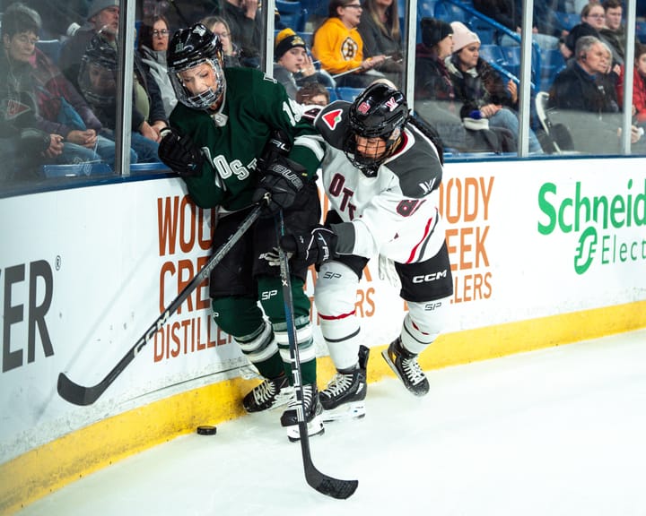 Marvin and Adzija battle for the puck in the corner. Marvin is on the inside in green, Adzija outside in white.