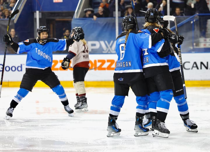 Toronto players celebrate a goal against Montréal. They are in a group hug and wearing blue home jerseys.