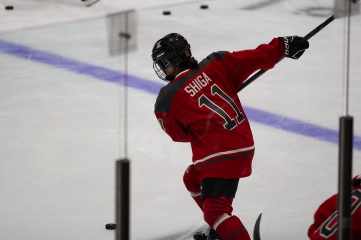 Akane Shiga, wearing a red PWHL Ottawa jersey, winds up to take a shot.