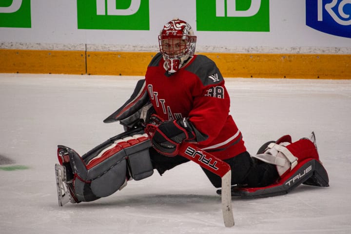 Emerance Maschmeyer stretches on the ice in her goalie equipment. 