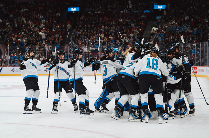 Toronto players celebrate their overtime win over Montréal with a team-wide group hug. They are all in white.