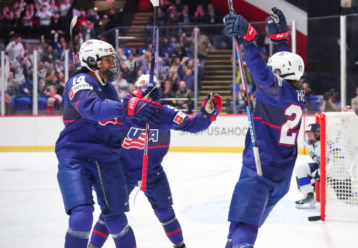 Edwards (ledt) goes to celebrate her third goal with a group hug featuring Taylor Heise (right) and another teammate (back)