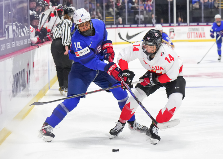 Edwards (left) and Fast (right) battle over the puck. Their sticks are crossed and the puck sits between them.