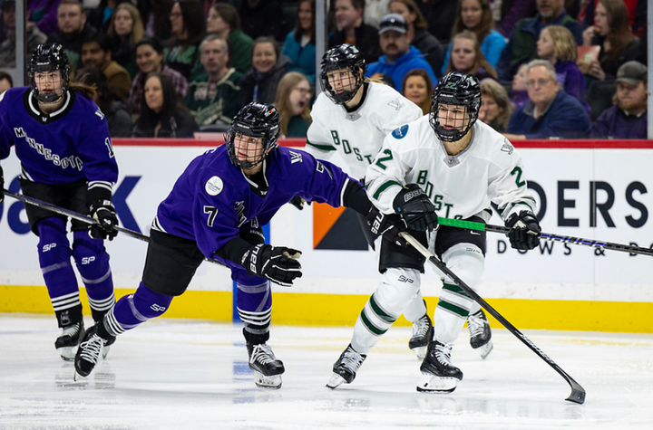 DiGirolamo (right in white) and Butorac (left in purple) hunt for the puck. Butorac is pushing DiGirolamo with her left hand.