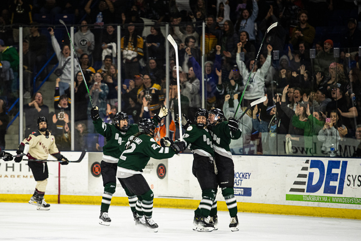 Three Boston players go in for a group hug with Fratkin after she scored. They're smiling and wearing green home uniforms.