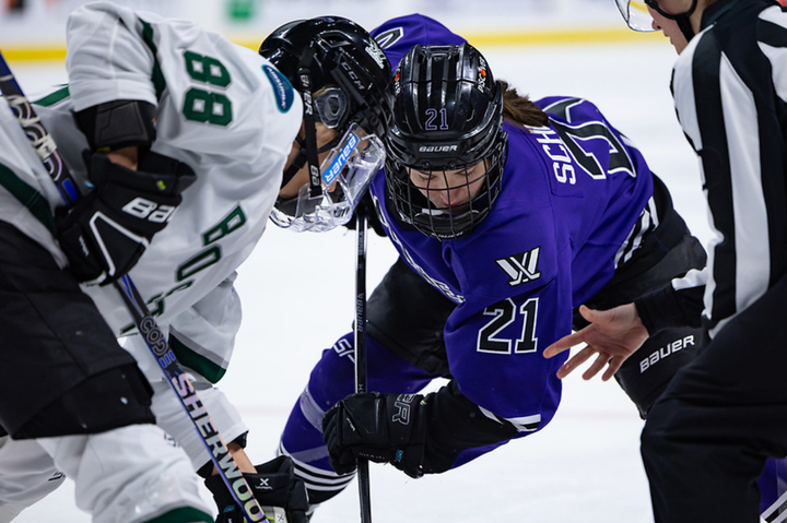 Tapani (left in white) takes a face off against Schepers (right in purple). They're both crouched with their sticks down.