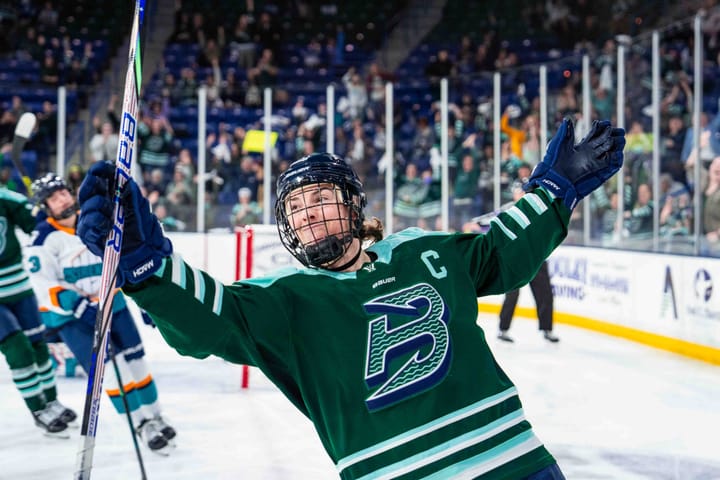 Knight raises her wide-open arms and smiles as she skates toward the corner. She's wearing a green home uniform.
