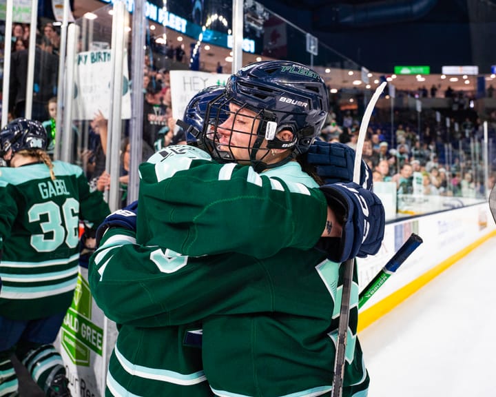 Pejšová (right) tears up as she embraces her teammate. They are both wearing green home uniforms.