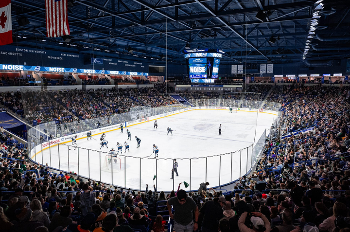 A wide-angle shot of Fleet and Sirens players lining up for a faceoff. The stands surrounding the ice are packed with fans.