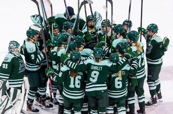 The Fleet celebrate their win with a tight group hug at center ice. They are all wearing green home uniforms.